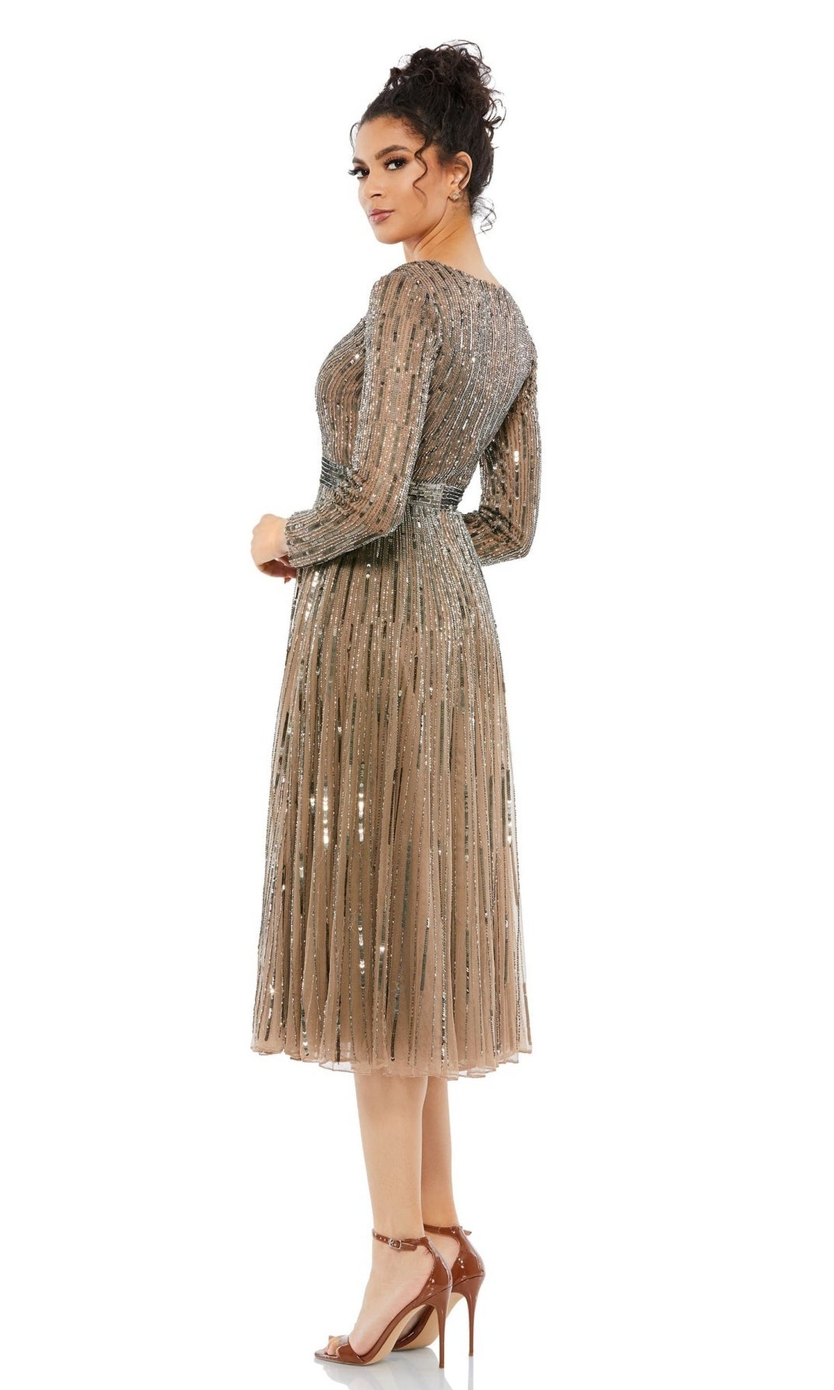 A woman wearing the Short Semi-Formal Dress 5528 by Mac Duggal, a knee-length metallic sequin A-line dress with long sleeves and high-heeled sandals, stands facing slightly away from the camera.